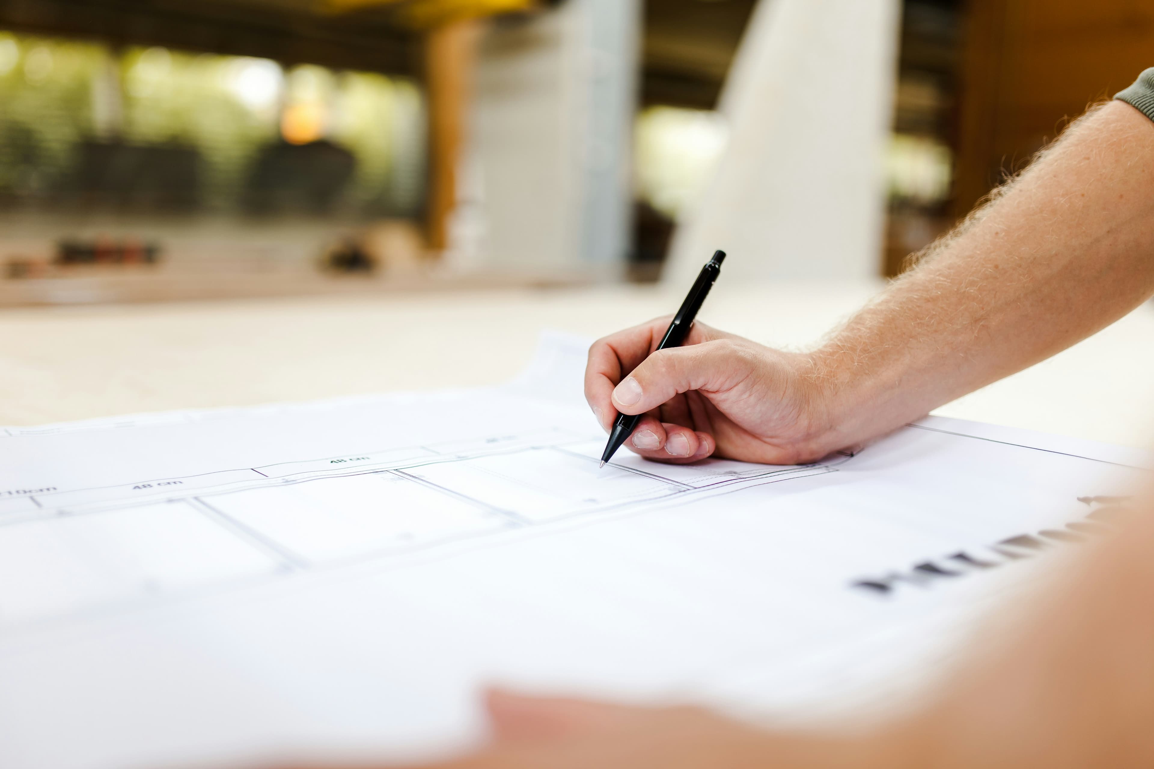 A tradesman sketching building plans on a workbench