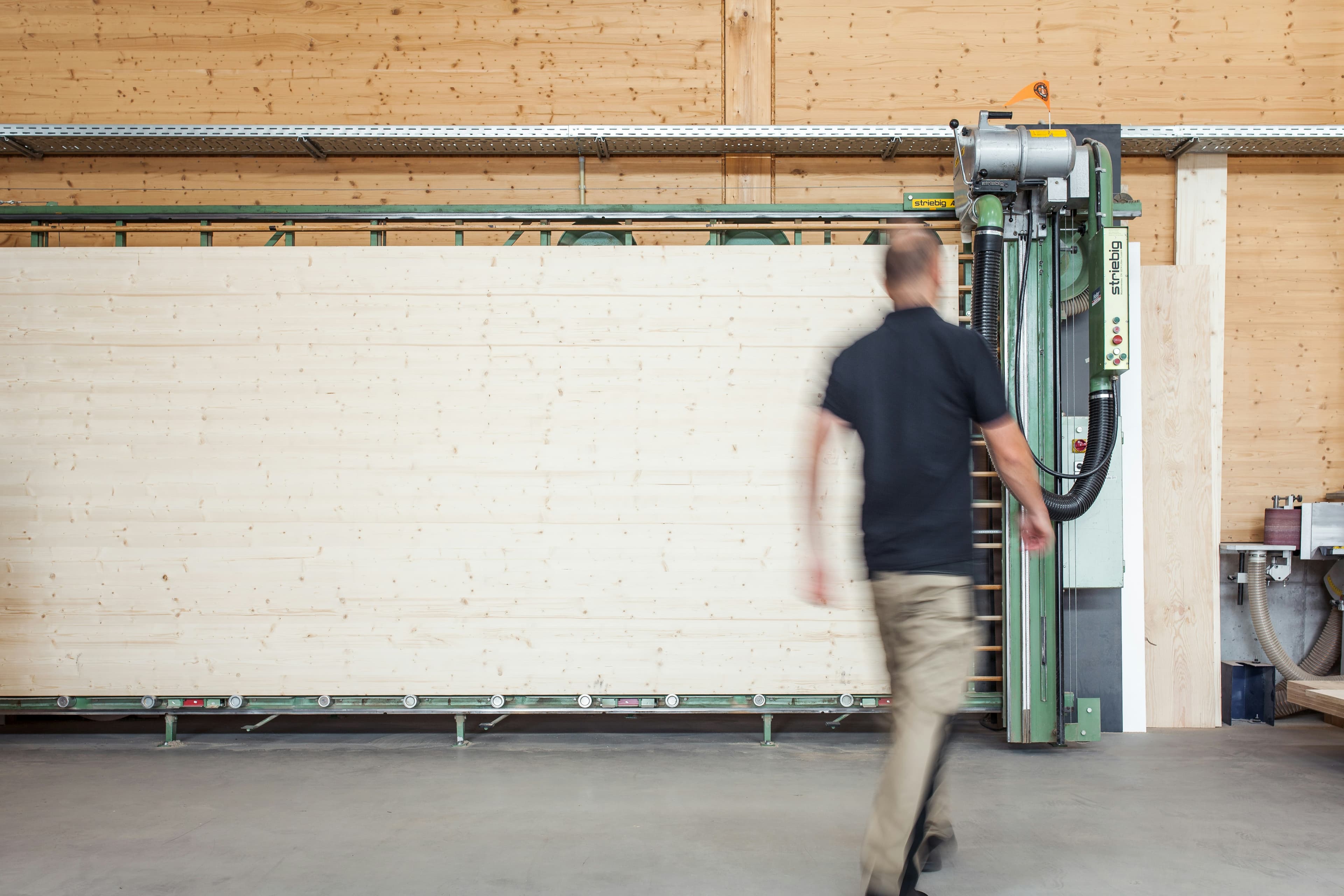 A carpenter walking through a bright workshop